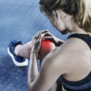 Woman sitting on the floor displaying knee pain