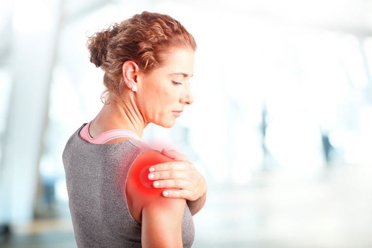 woman holding her shoulder to display shoulder pain