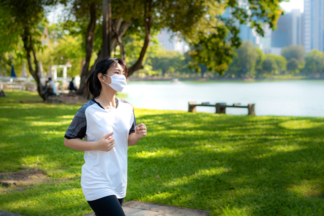 woman running in the park with a mask on