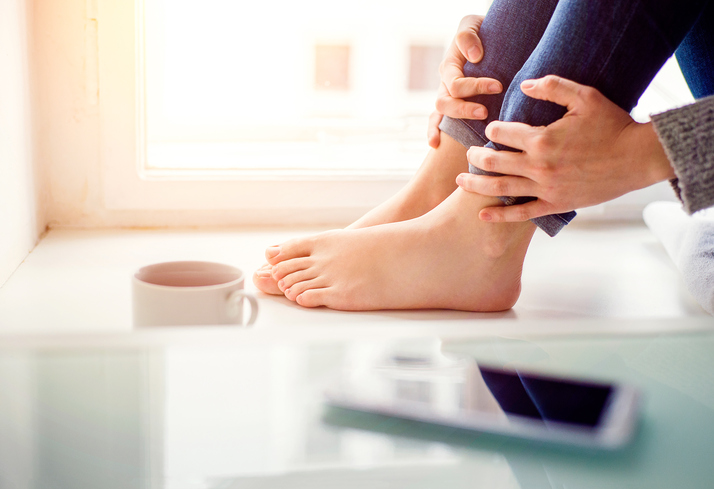 Woman with flat feet holding ankles