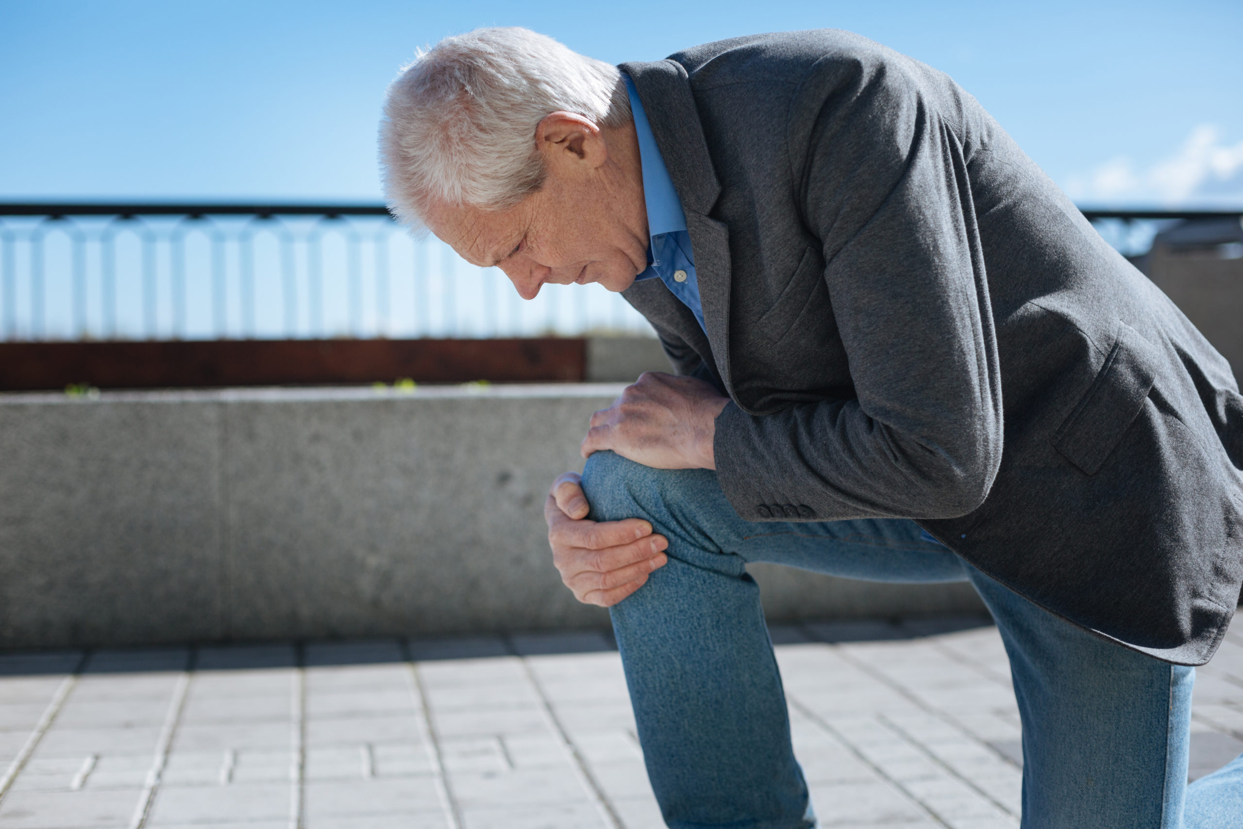 Man holding knee, ready for joint replacement surgery